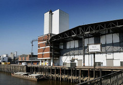 Die Ladung einer Schute wird gelöscht - über eine Sauganlage wird das Schüttgut in den Speicher transportiert. Eisendalben vor der Kaianlage dienen zum Festmachen der Schiffe.
