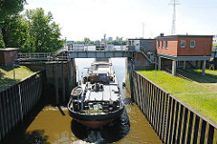 Ein Binnenschiff hat seine Fracht im Hamburger Hafen gelöscht und fährt ohne Ladung durch das geöffnete Schleusentor der Reiherstiegschleuse.