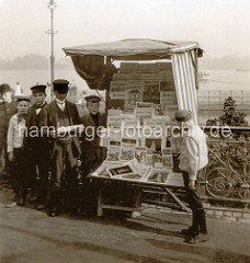 Zeitungsstand mit Zeitungsjungen am Hamburger Jungfernstieg, im Hintergrund die Binnenalster.