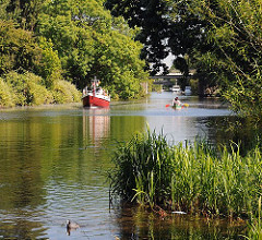 Der Ernst-August-Kanal ist ein interessantes Freizeitrevier in Hamburg Wilhelmsburg. Ein Motorboot fährt den Kanal Richtung Ernst-August-Schleuse, Kanuten paddeln.