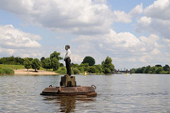Auf der Süderelbe bei Hamburg Stillhorn schwimmt eine der vier Holzskulpturen die zu dem Gesamtkunstwerk "Vier Männer auf Bojen" gehören.