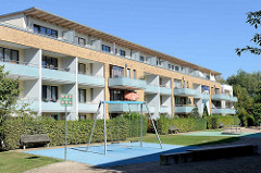 Kleiner Kinderspielplatz mit Schaukel und Karussell an der Balkon-Front / Sonnenseite eines Neubaus in Hamburg Bramfeld.