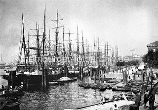 Historische Aufnahme vom Hamburger Niederhafen; Ruderboote liegen am Ponton - Segelschiffe an den Dalben.