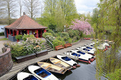 Frühling in Hamburg - Blick auf die Liebesinsel  im Stadtparksee;Tretboote am Steg, roter Pavillon und rosa blühende Zierkirsche.