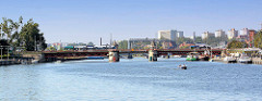 Blick über die Oder zur Autobrücke in Stettin; Fahrgastschiffe und Sportboote liegen an der Promenade - im Hintergrund Hochhäuser.