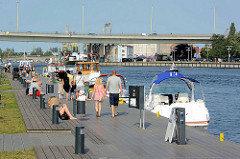 SpaziergängerInnen und Sportboote an der Stettiner Uferpromenade der Oder - Autobrücke über den Fluss.