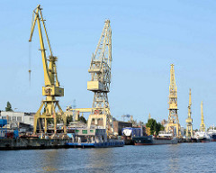 Kaianlage an der West-Oder in Stettin; Gewerbearchitektur und Hafenkräne - Schiffe liegen an der Kaimauer.