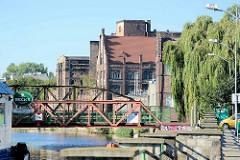 Historische Industriearchitektur / Ziegelgebäude im Hafen von Stettin; eine Eisenbrücke führt über den Hafenkanal der West-Oder
