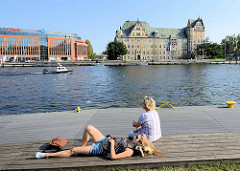 Entspannung an der Uferpromenade der Oder in Stettin; Holzbänke am Flussufer Laden in der Sonne zum Verweilen ein; man kann den Bootsverkehr auf dem Fluss beobachten.
