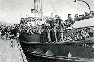 Ein dicht besetztes Motorboot legt am Steg im Hamburger Hafen  am Baumwall an; Hafenarbeiter kommen von der Schicht .