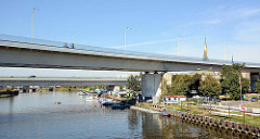Moderne Autobrücke über einen Hafenkanal Stettiner Hafengebiet; Sportboote liegen unter der Brücke am Steg.