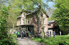 Außenansicht der unter Denkmalschutz stehenden  Villa Mutzenbecher, blühender Rhododendron vor der Holzveranda.