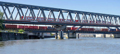 Eisenbahnbrücken am Billehafen / Oberhafenkanal in Hamburg Rothenburgsort; ein Containerzug / Güterzug beladen mit Containern sowie eine S-Bahn überqueren den Kanal.