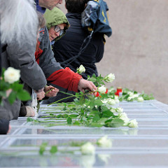 Die Tafeln mit den Namen der über 8000 deportenierten Juden, Sinti und Roma werden zum Gedenken mit weissen Rosen geschmückt.