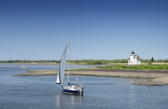 Einfahrt zum Dwarsloch - Haseldorfer Binnenelbe - ein Segelboot unter Segel, blauer Himmel.