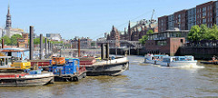 Arbeitsschiffe liegen im Hamburger Binnenhafen,  ein Fahrgastschiff mit Touristen besichtigt  die Speicherstadt - Fußgänger auf der Kehrwiederbrücke.