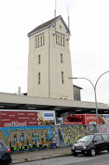 Schlachthofgelände in Lehe / Bremerhaven; Mauer mit Graffiti / Turm mit Spitzdach und Antennen.
