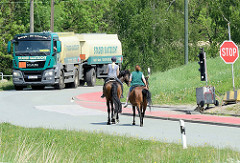 Straßenverkehr am Obergeorgswerder Hauptdeich, ein Tanklastwagen  wartet an der Ampel,  zwei Reiterinnen zu Pferd überqueren die Straße.
