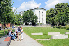 Grünanlage mit Sitzbänken / Ruheplätzen auf der Harburger Schlossinsel - im Hintergrund das Harburger Schloss, das als Wohngebäude genutzt wird.