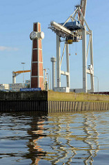 Pegelturm und Schild Segelschiffhafen im Hamburger Hafen, dahinter eine Krananlage vom Hansahafen.