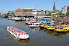Barkasse und Arbeitsboote liegen im Hamburger Binnenhafen / Hafenbecken in Hamburg-Altstadt; ein Fahrgastschiff bei einer Fleetrundfahrt.