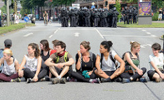 Demonstration Bildungsstreik  - Jugend Gegen G20 in Hamburg; TeilehmerInnen sitzen in der Sonne am Millerntor - im Hintergrund wartende Polzisten in Kampfmontur.