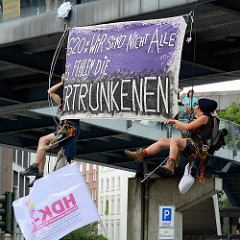 Zwei Demonstrant*innen haben sich von einer Fussgängerbrücke abgeseilt und ein Transpartent aufgehängt: G20: Wir sind nicht alle, es fehlen die ERTRUNKENEN.