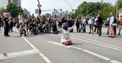 Fotografen bei der Arbeit beim Protest gegen den G 20 Gipfel in Hamburg, eine Demonstrantin sitzt alleine vor einer Polizeikette und hebt die Arme.