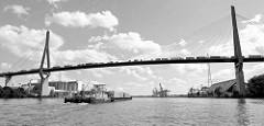 Lastwagenverkehr mit Containern auf der Köhlbrandbrücke über die Hamburger Süderelbe - ein Schubschiff schiebt einen Leichter, der mit Containern beladen ist.