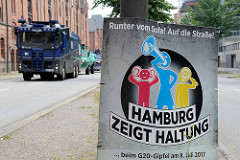 Plakat in der Hafencity - Runter vom Sofa! Auf die Straße - Hamburg zeigt Haltung beim G20-Gipfel am 8. Juli 2017; im Hintergrund Wasserwerfer.