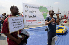 Sprecher und Transparente gegen den G 20 Gipfel in Hamburg; neokoloniale Ausbeutung von Afrika durch G20 - Freihandel Macht Flucht.
