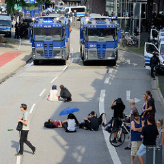 Colour the Red Zone - Protest gegen den G 20 Gipfel in Hamburg, Demonstranten ruhen sich im Schatten auf der Straße aus - Wasserwerfer stehen zur Abkühlung bereit.