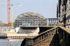 Blick über die Norderelbe zum Kirchenpauerkai und der Baustelle / Stahlkonstruktion vom Bahnhof Elbbrücken; re. die Freihafenelbbrücke mit einem historischen Treppenabgang / Steintreppe mit Treppengeländer, Säulen.