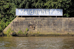 Kaimauer und altes blaues Hafenschild mit Namen des Hafenbeckens Moldauhafen im Hamburger Hafen.
