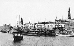 Historische Hafenszene am Ufer der Düna in Riga; Dampfer und Segelschiffe liegen am Kai - Kirchturm der Petrikirche und vom Rigaer Dom.