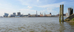 Blick von der Einfahrt des Moldauhafens über die Norderelbe zum Strandkai und der Hamburger Hafencity - re. eine alte Holzdalbe und das Veddelhöft, lks. die Elbphilharmonie.