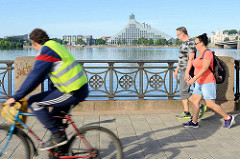 Blick von der Flusspromenade zur Lettischen Nationalbibliothek; fertig gestellt 2014, Architekt Gunnar Birkerts. Radfahrer und Fussgänger am Flussufer.