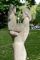 Steinskulptur Mutter mit Kind in der Grünanlage vor der Kirche Zum Guten Hirten in Hamburg Stellingen / Langenfelde.