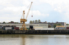 Gewerbebetrieb - Kran am Kai des Saalehafens im Hamburg Kleiner Grasbrook; im Hintergrund Wohnhäuser auf der Veddel.