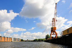 Blick in den Saalehafen im Hamburger Hafenstadtteil Kleiner Grasbrook; re. Kaianlage mit Kran und Container-Lastzug - re. Speichergebäude und Parkhaus am Dessauer Ufer.