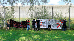 Solidaritäts-Demonstration vom S-Bahnhof Billwerder zu den No-G20 Gefangenen in der JVA Hamburg-Billwerder am 03.09.2017 . Transparente werden am Gefängniszaun aufgehängt, dahinter die Gefängnismauer.