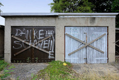 Alte Garagen mit Holztüren - die Tore sind mit Holzkreuzen vernagelt, Aufschrift Danke ihr Schweine -  Bilder aus Torgau / Elbe.