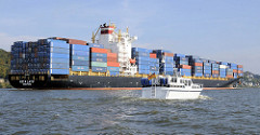 Der Containerfrachter Kota Latif fährt mit Container beladen auf der Elbe Richtung Hamburger Hafen - ein Sportboot überholt den Frachter.