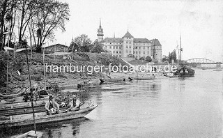 Historische Ansicht vom Elbufer bei Torgau; Fischerkähne und Ewer liegen am Strand - im Hintergrund Schloss Hartenfels und die Elbbrücken.