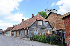 Typische Holzhäuser, Wohnhäuser mit Holzfassade und Fensterluken - Kuldīga / Lettland.