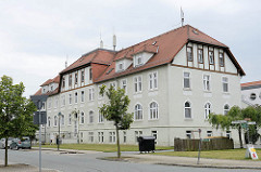 Mehrstöckiges Gebäude mit Krüppelwalmdach in der Reinhold Kirsten Straße; jetzt Sitz Sozialer Dienste + Seniorenheim.