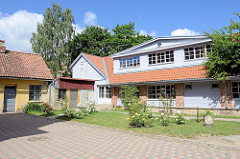 Holzgebäude als Neubau - angrenzende alte Schuppen, blühende Rosen im Innenhof; Architekturbilder in Kuldīga / Lettland.