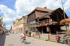 Geschäftsstraße / Fussgängerzone Baznīcas iela  in Kuldīga / Lettland. Holzhaus, Restaurant mit Holzterrasse.
