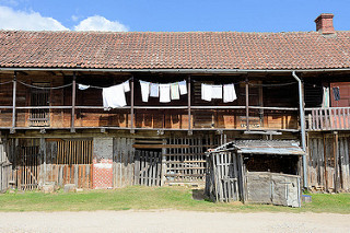 Schuppen mit Laubengang, Holztüren - Wäsche hängt zum Trocknen in der Sonne. Architekturbilder in Kuldīga / Lettland.