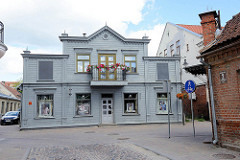Historische Holzarchitektur - Fassade taubenblau gestrichen, Eisenbalkon mit roten Geranien; Architekturbilder aus Kuldīga / Lettland.